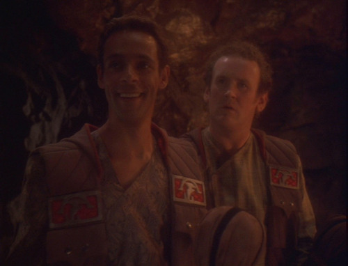 Bashir and O'Brien in brown outfits with Klingon symbols, in the cave where the bachelor party is held