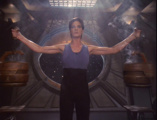 Jadzia holds two steaming, heavy braziers aloft, one in each hand