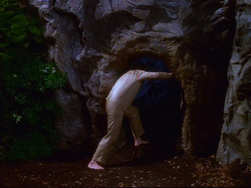 Chakotay in brown clothes goes into a cave