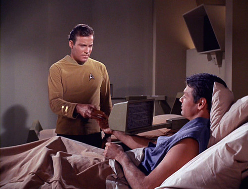 Mitchell reads a book on a computer screen in sickbay