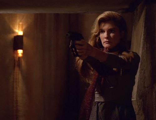 Janeway holds a weapon out to threaten the prison guards