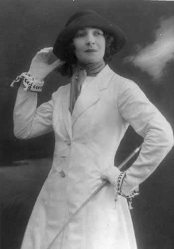 A young Celia Lovsky poses for the camera in a white dress, dark hat and gloves
