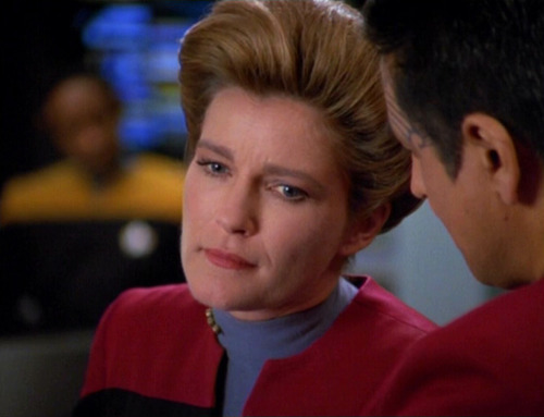 Janeway listens to Chakotay on the bridge