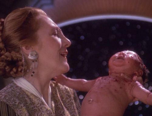 Bajoran midwife lifts up Kirayoshi after the birth