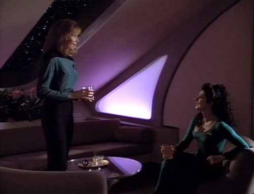 In her quarters, Crusher stands and talks to Troi, seated
