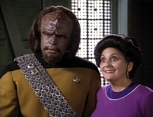 Worf stands beside an excited Helena in the transporter room