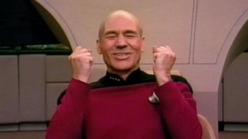 Picard smiling and holding his fists up as if to say, "Yes!"