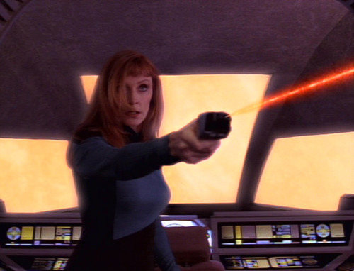 Crusher fires a phaser at Jo'Bril in the shuttle