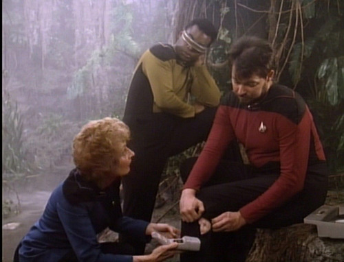 Pulaski looks at Riker's injury while La Forge watches