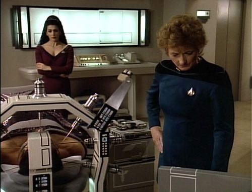 Pulaski treats Riker while Troi watches