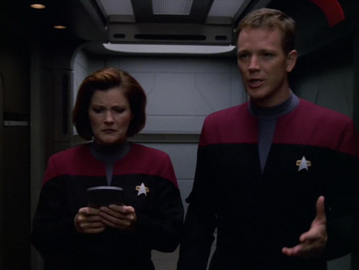 Janeway looks concerned at the PADD Paris has handed her