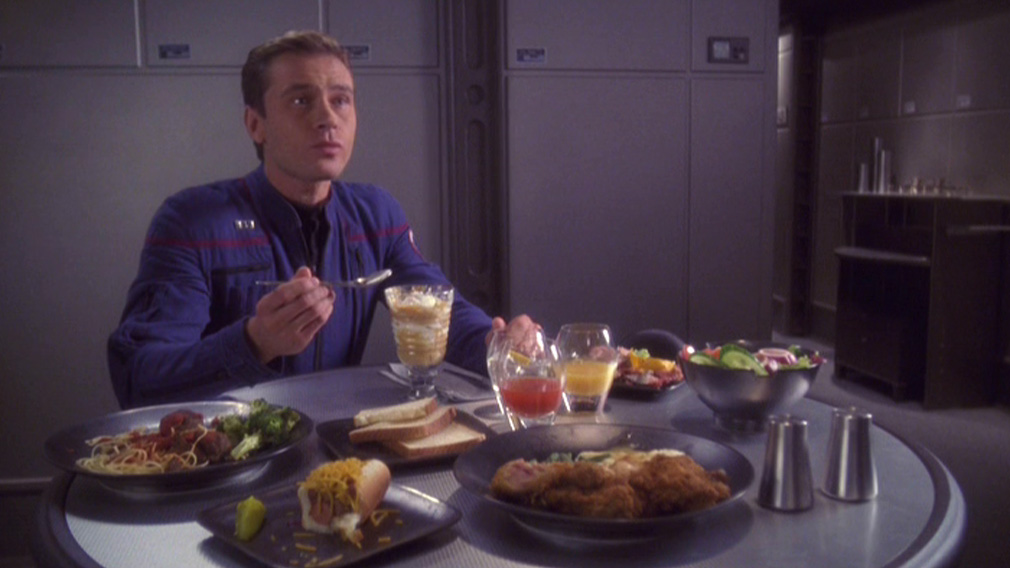 Trip sitting at a table full of food in the mess hall
