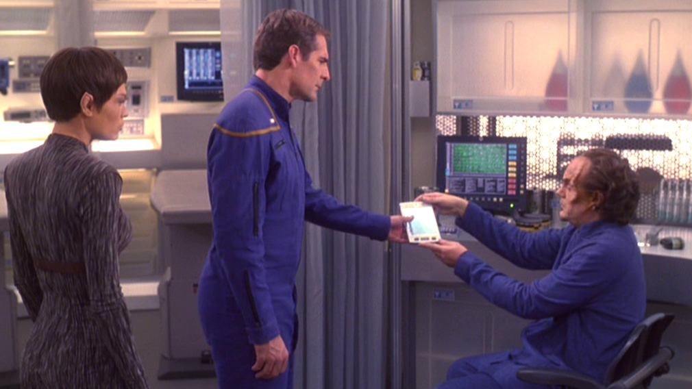Phlox hands a padd to Archer while T'Pol looks on