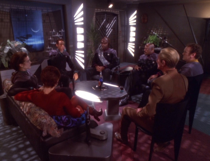 Bashir talks to the senior staff in Sisko's living room