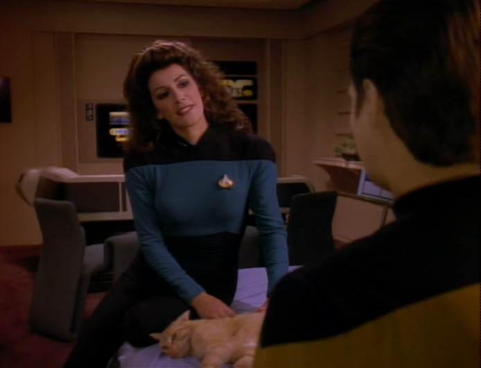 Troi perches on Data's bed next to Spot, talking to Data about dreams and Freud