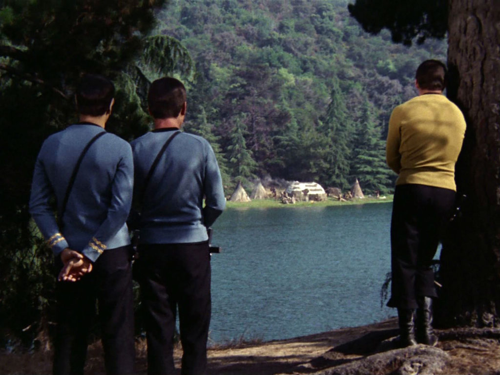Kirk, Spock and McCoy stare across the lake at a Native American village