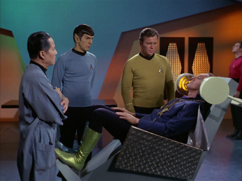 Garth in the rehabilitation chair as Cory, Spock and Kirk look on